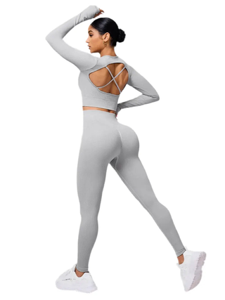 Woman wearing light gray back crisscross long sleeve top and leggings activewear set