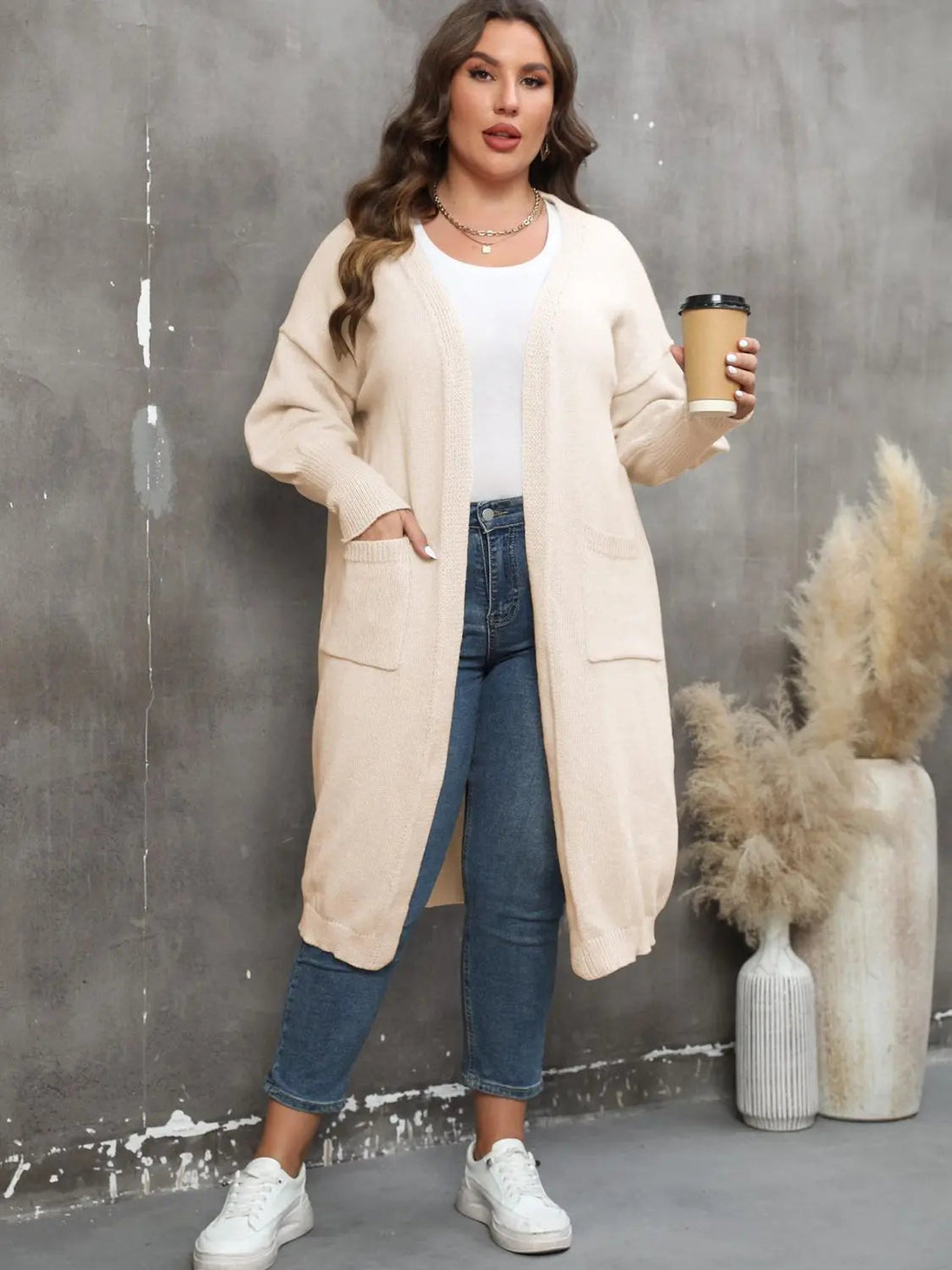 Plus size long sleeve pocketed cardigan in beige with open front and ribbed texture, styled with casual jeans and white sneakers