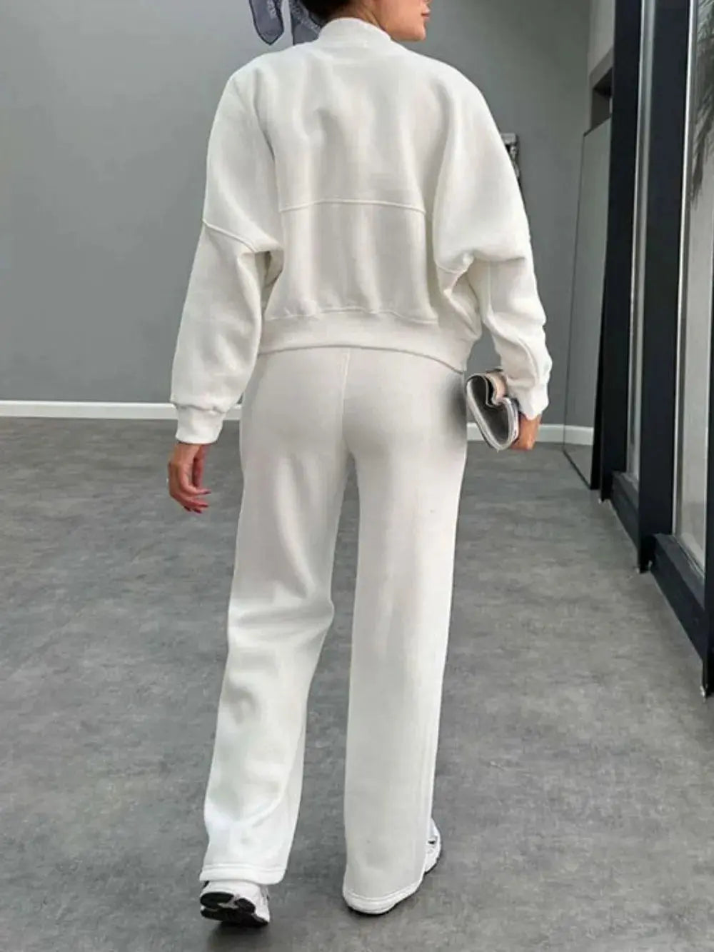 Woman wearing white baseball collar zip up outerwear and drawstring pants set standing indoors