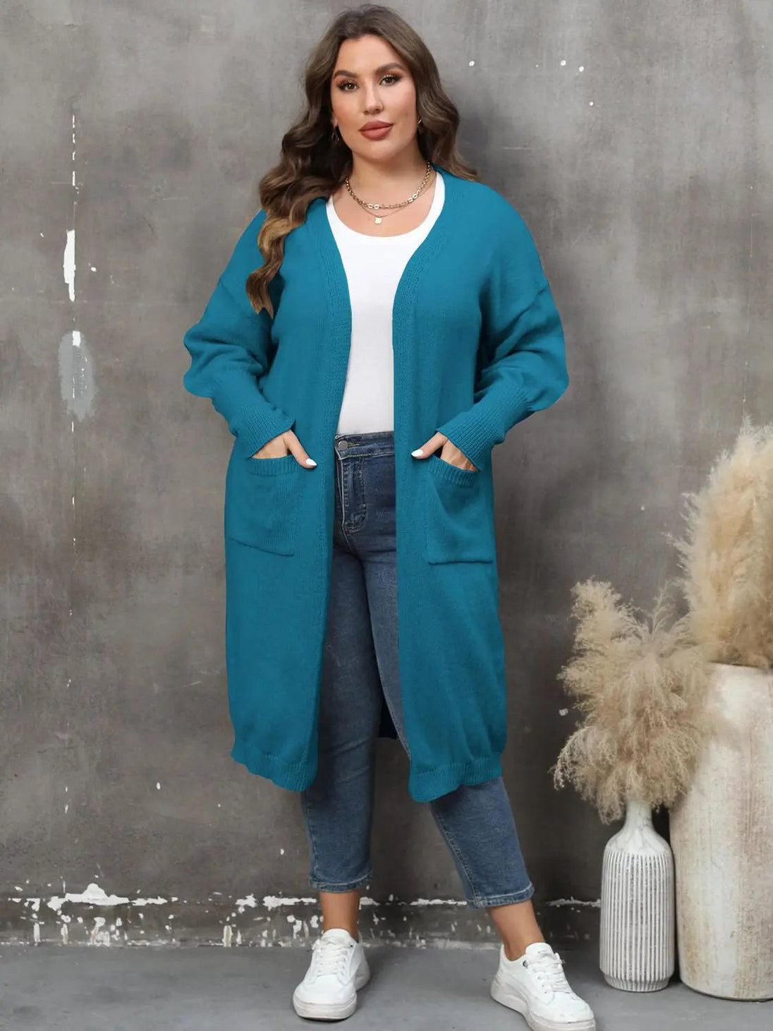 Plus size long sleeve teal cardigan with pockets and open front, worn with white top and jeans