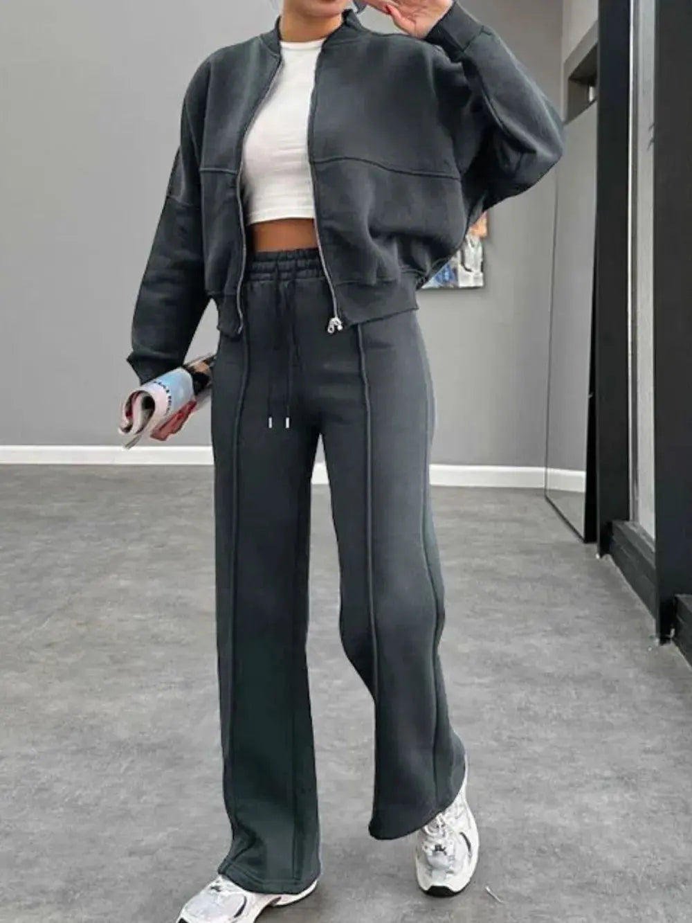 Woman wearing black baseball collar zip up outerwear and drawstring pants set with white sneakers