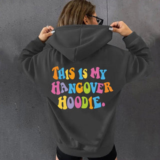 Woman wearing oversized black hoodie with colorful "THIS IS MY HANGOVER HOODIE" back print and drop shoulder design