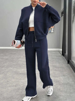 Woman wearing navy baseball collar zip up outerwear and drawstring pants set with white sneakers in modern room