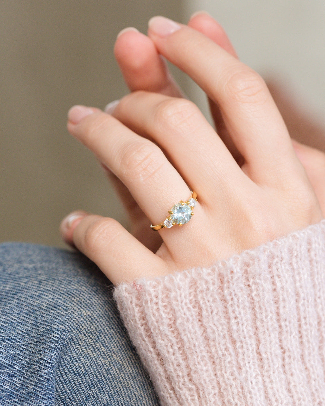 Blue topaz three stone ring in 18k gold vermeil worn on hand with pink sweater background
