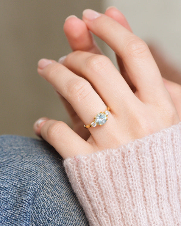 Blue topaz three stone ring in 18k gold vermeil worn on hand with pink sweater background