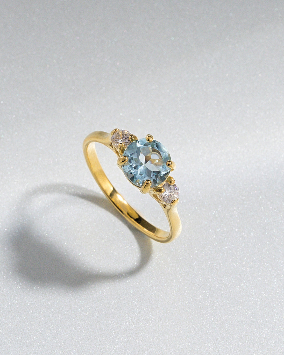 Blue topaz three stone ring with round cut sky blue topaz and simulated diamonds set in 18k gold vermeil.