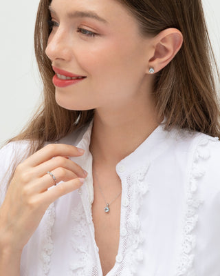 Woman wearing blue topaz everyday jewellery set with sterling silver necklace, ring, and stud earrings