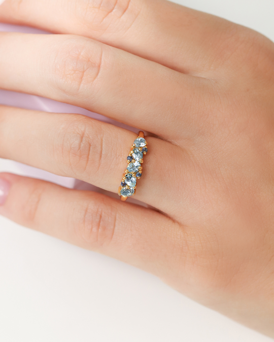 Blue Sapphire and Blue Topaz pear cut half eternity band in 18k gold vermeil on hand wearing ring