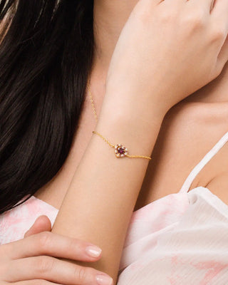 Close-up of a woman's wrist and neck wearing an 18k gold vermeil bracelet and pendant necklace with red heart rhodolite garnet gemstones.