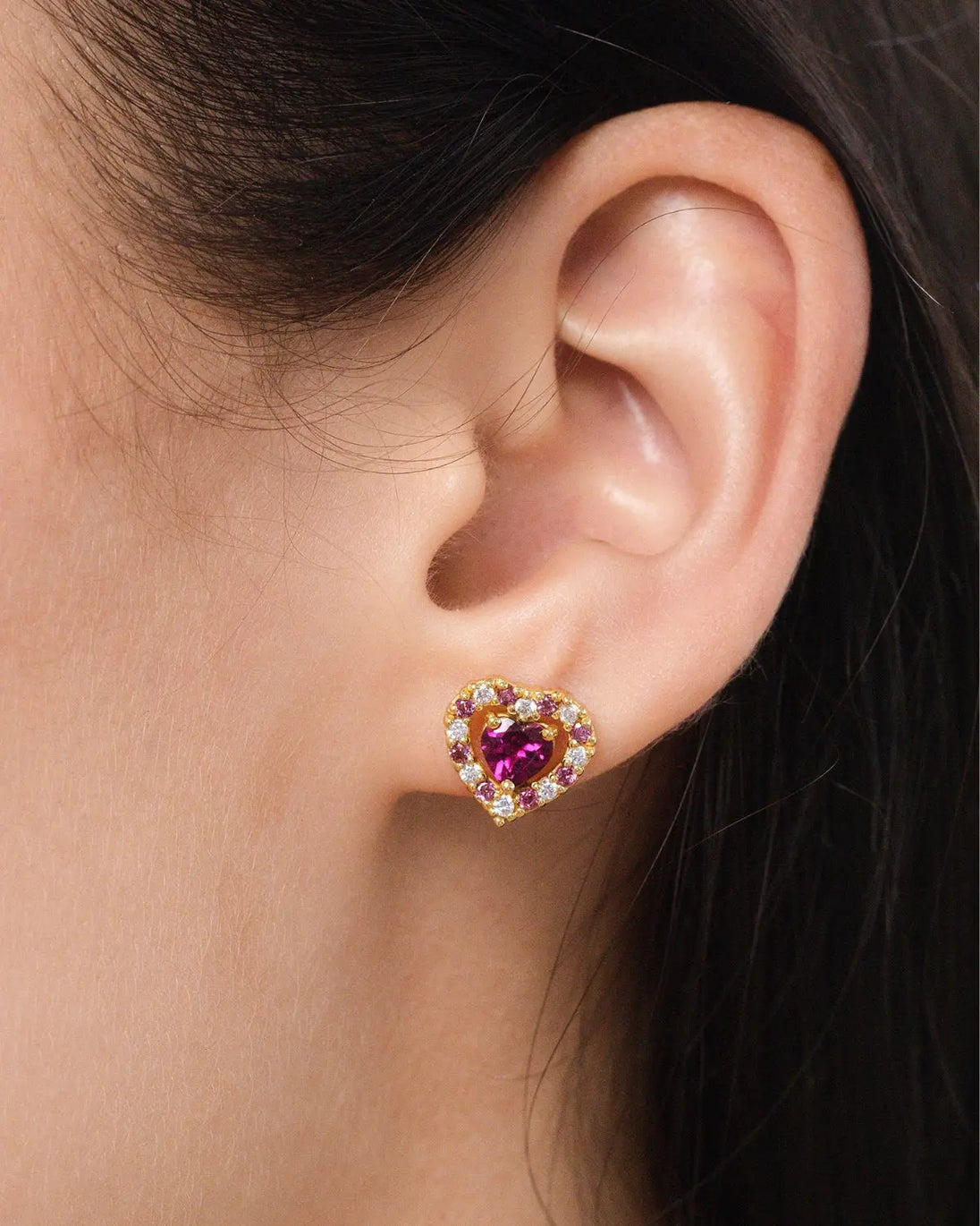 Close-up of red heart rhodolite garnet stud earring in 18k gold vermeil worn on ear