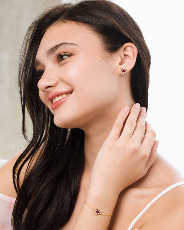 Woman wearing red heart rhodolite garnet earrings and bracelet in 18k gold vermeil jewelry set
