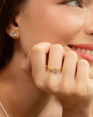 Close-up of woman wearing blue topaz jewelry ring and stud earrings in 18k gold vermeil