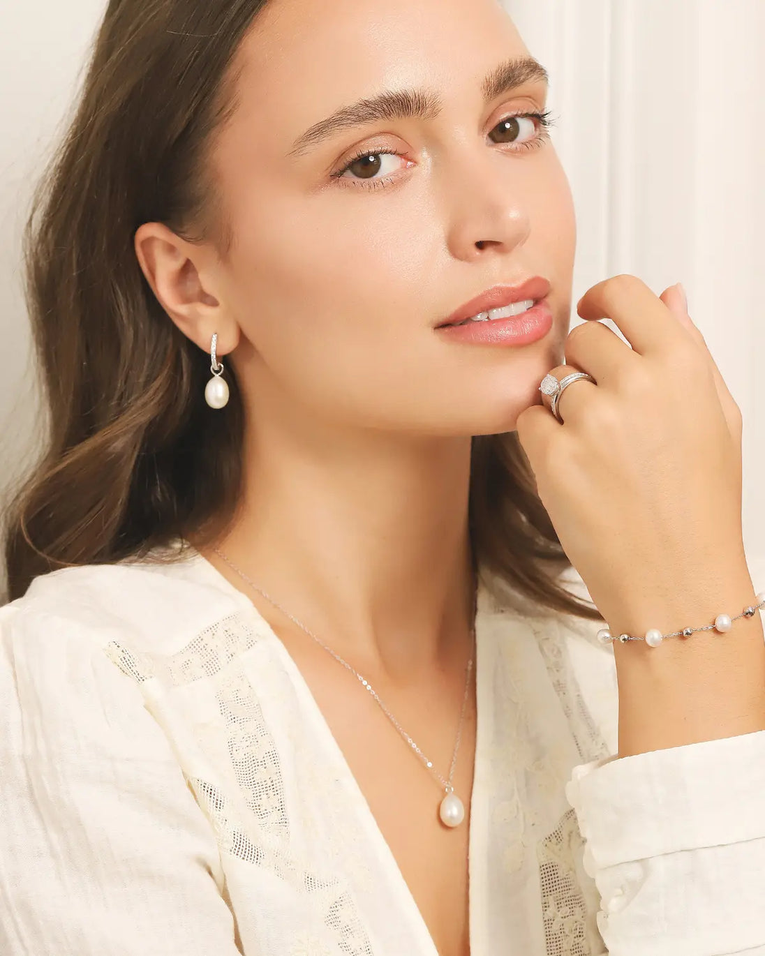 Woman wearing natural freshwater pearl bracelet in sterling silver with matching pearl necklace and earrings