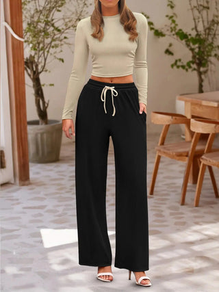 woman wearing round neck long sleeve beige top and black drawstring pants set indoors