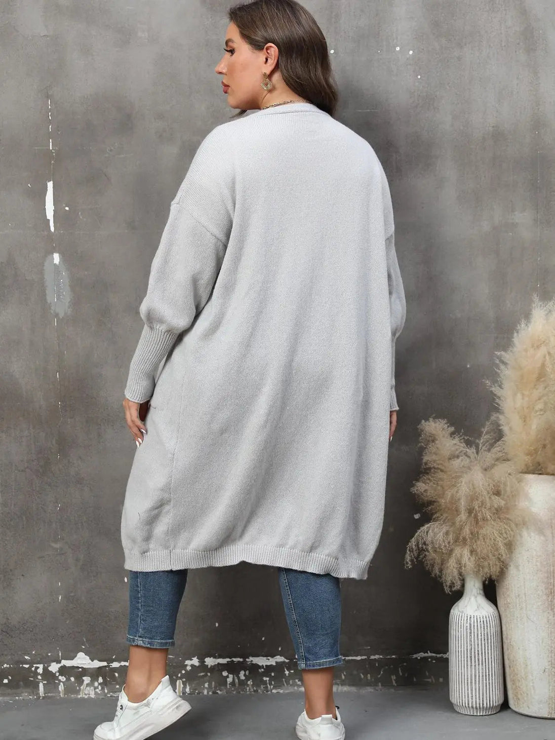 Plus size long sleeve gray ribbed cardigan with pockets and open front worn with jeans and white sneakers