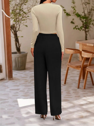 Woman wearing round neck long sleeve top and black pants set from the back in a cozy room