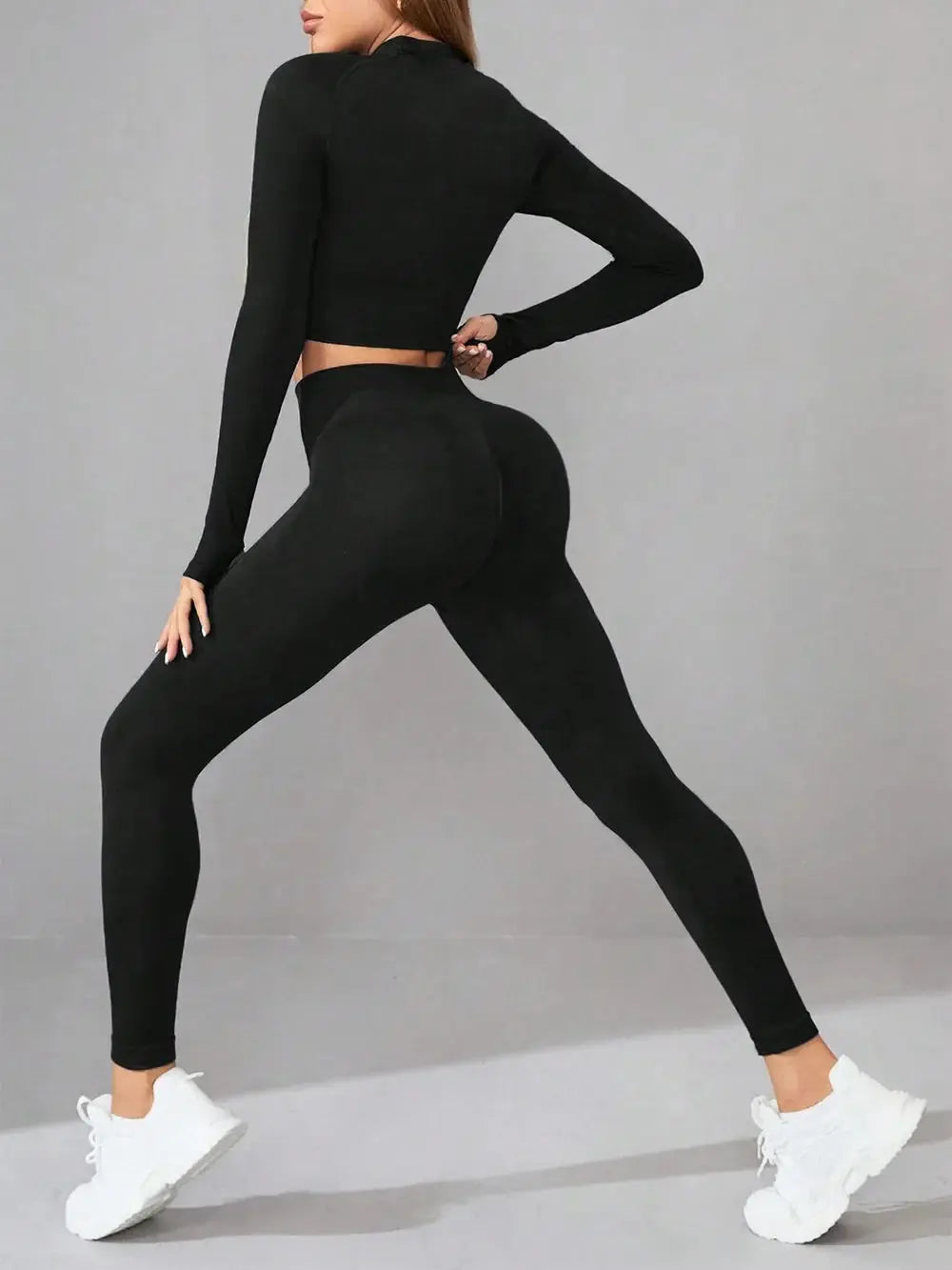 Woman wearing black mock neck long sleeve top and leggings active set in a yoga stretch pose