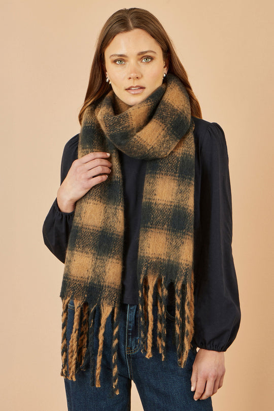 Woman wearing Yumi Brown Check Soft Scarf in brown and black with fringes, styled with a dark blouse and jeans