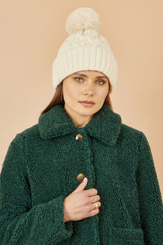 Yumi White Cable Knit Bobble Hat on woman wearing green fleece jacket