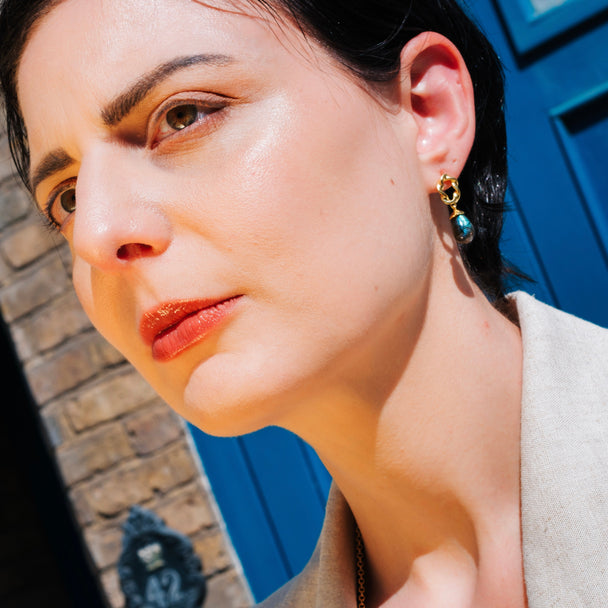 Moirai Twisted Loop Earrings with green onyx gemstone and 22k gold on recycled brass worn by woman