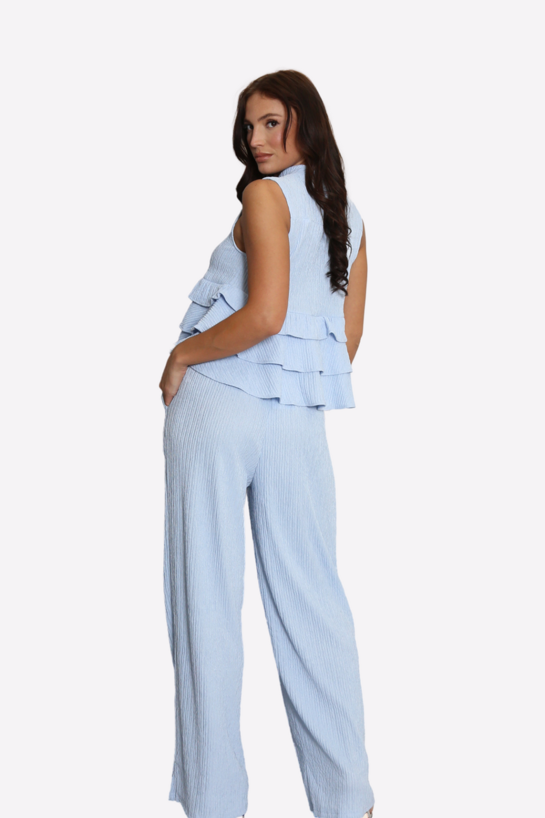 Woman wearing light blue high neck frill blouse and flared pants co-ord set from back view