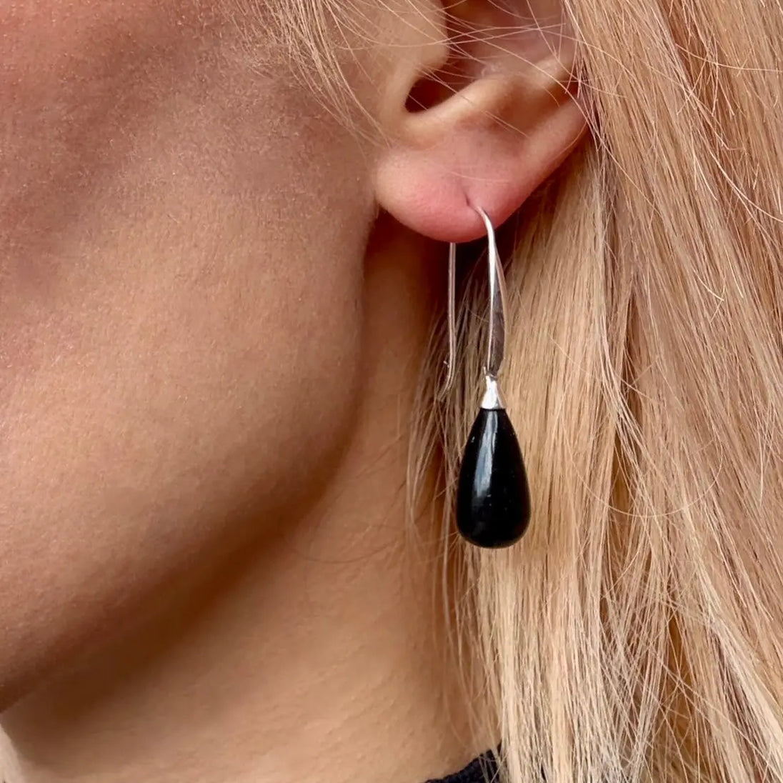 Woman wearing Hera polished stone drop earrings with black onyx teardrop stones and sterling silver hooks