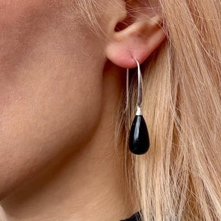 Woman wearing Hera polished stone drop earrings with black onyx teardrop stones and sterling silver hooks