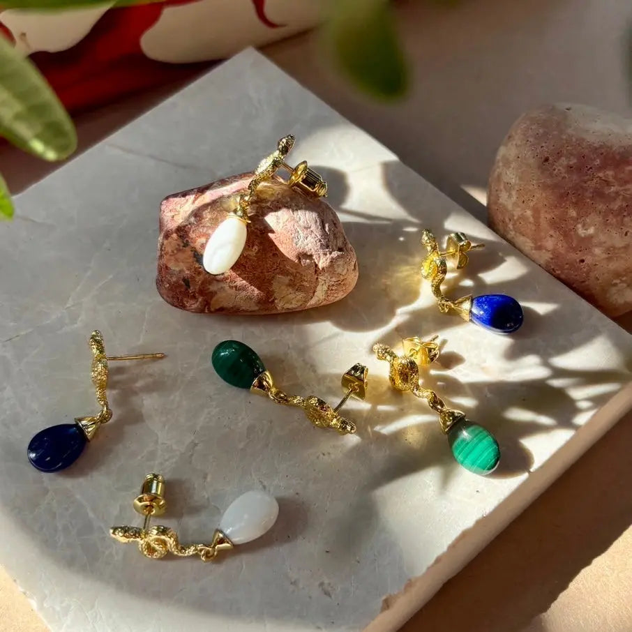 Medusa small gemstone drop earrings in 22k gold with lapis stones displayed on marble tray