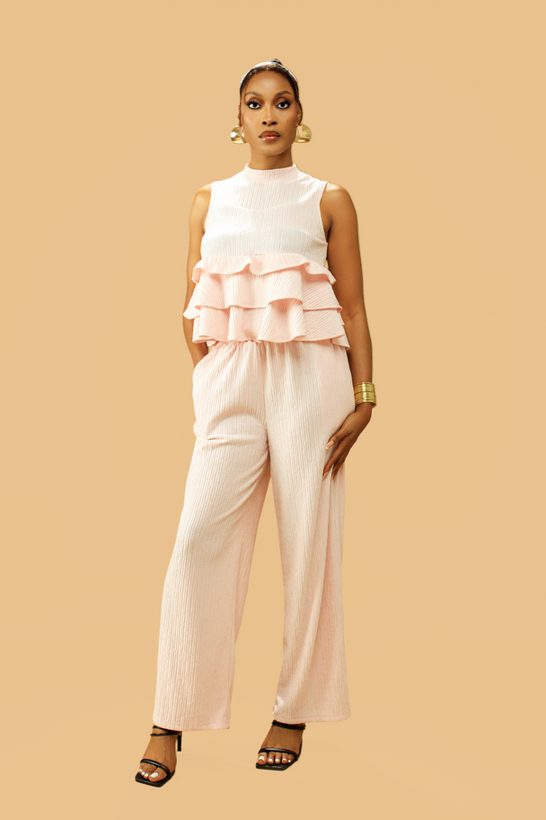 Woman wearing high neck frill blouse and flared pants co-ord set in blush pink