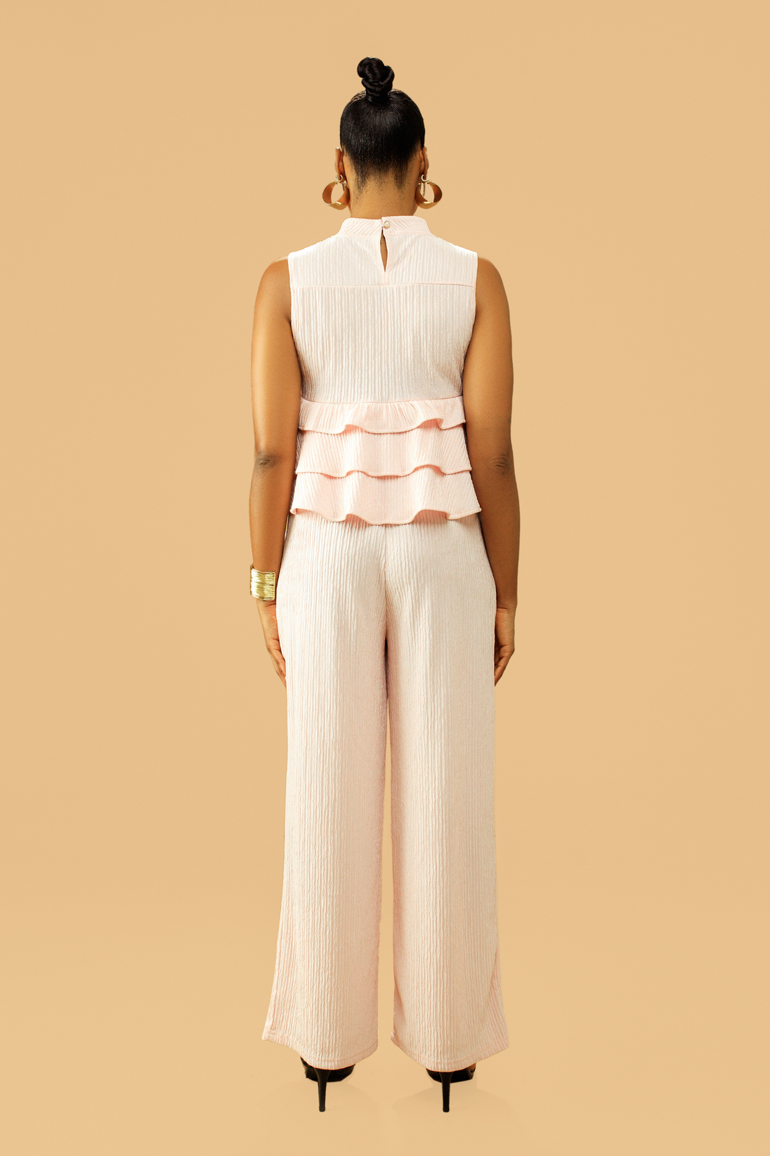 Woman wearing high neck frill blouse with flared pants co-ord set, back view.