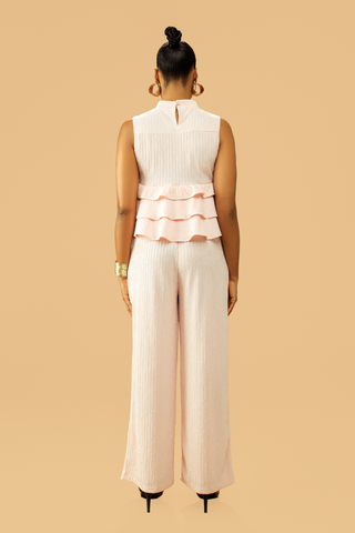 Woman wearing high neck frill blouse with flared pants co-ord set, back view.