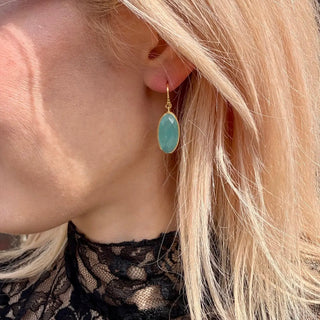 Close-up of Charis Oval Gemstone Earrings featuring Pariba Onyx set in 22K gold on recycled brass worn on ear