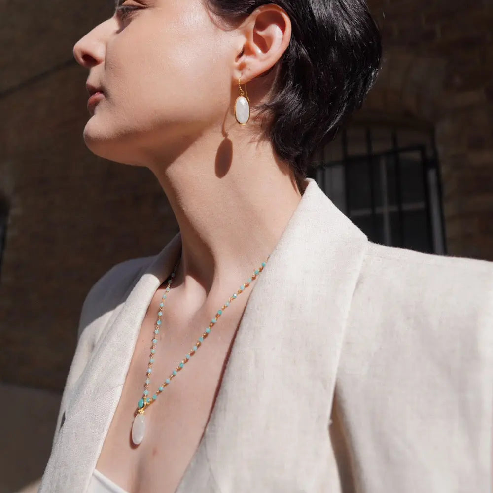 Charis Oval Gemstone Earrings Labradorite 22K gold drop earrings worn by woman with short hair and beige blazer