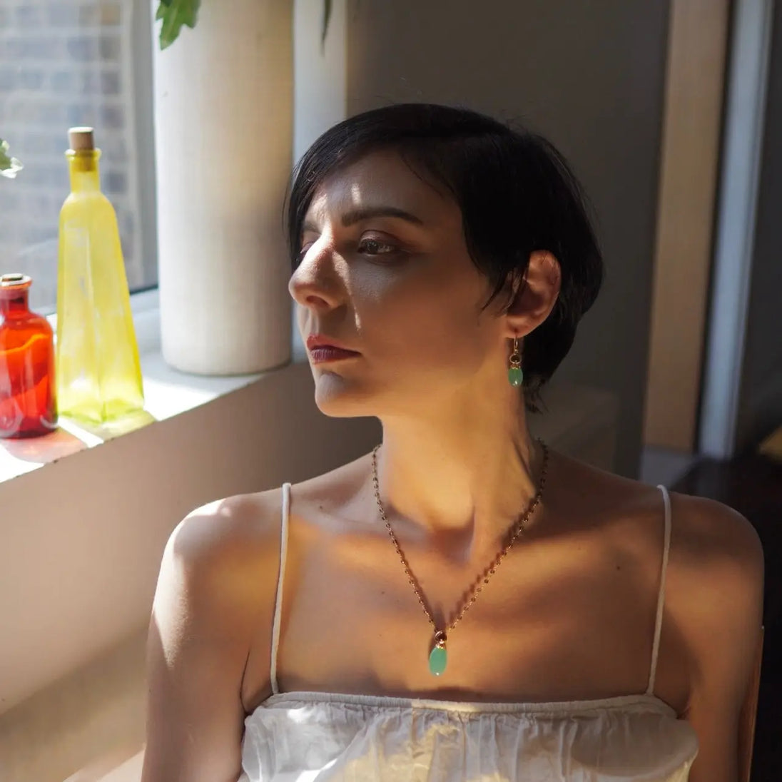Woman wearing Persephone Double Gemstone Earrings with Pariba Onyx and Smoky Quartz in gold setting