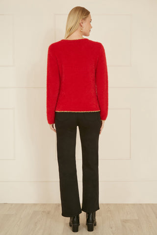 Back view of woman wearing red knitted fluffy Christmas star jumper paired with black pants and boots