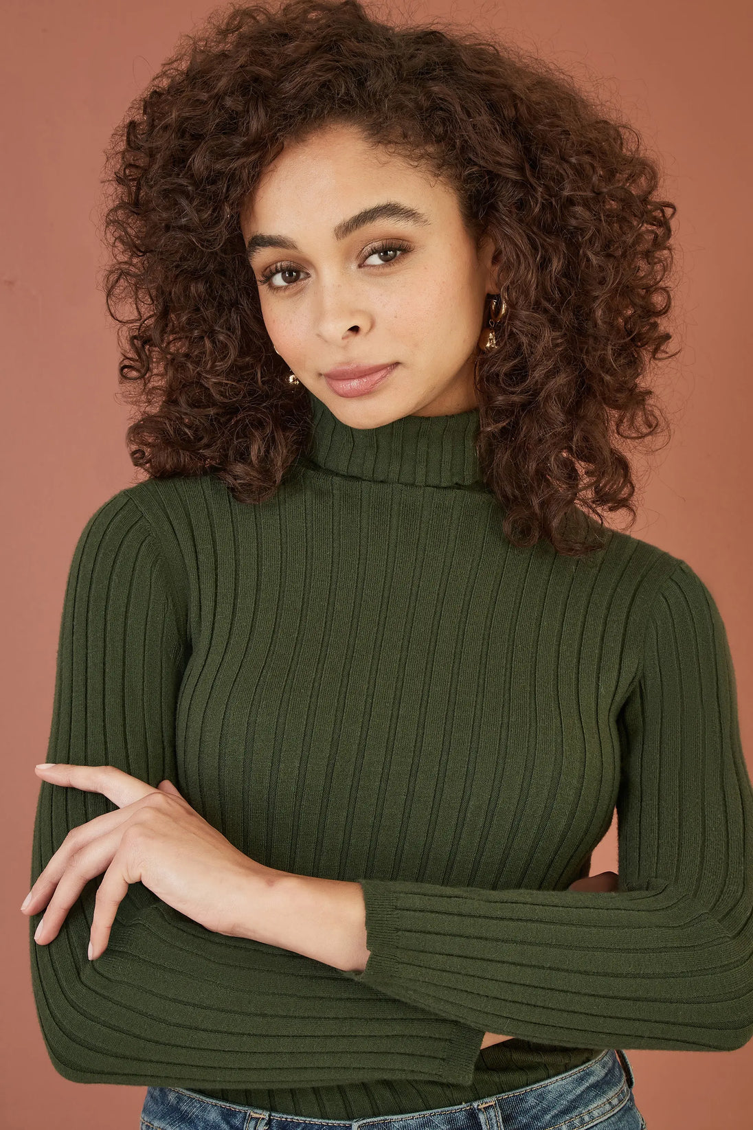 Woman wearing Yumi green ribbed knit roll neck jumper with long sleeves and fitted silhouette