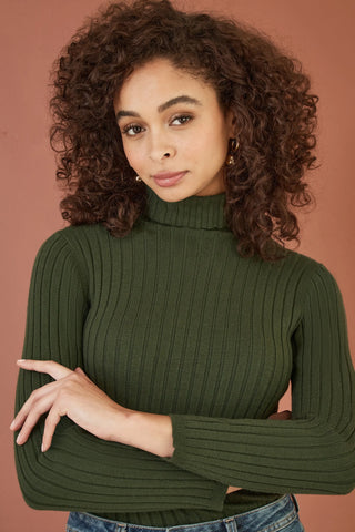 Woman wearing Yumi green ribbed knit roll neck jumper with long sleeves and fitted silhouette