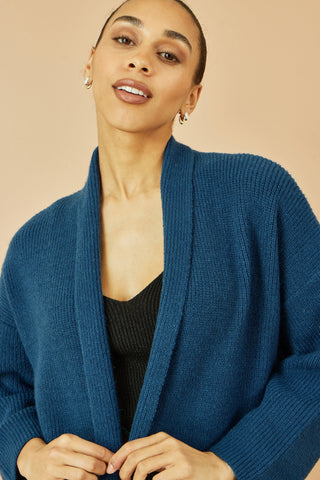 Woman wearing Yumi Teal Knitted Maxi Cardigan with pockets and vertical ribbed detail