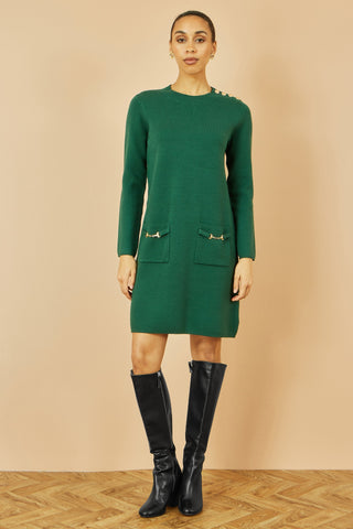 Yumi green knitted tunic dress with long sleeves, gold hardware on pockets and shoulder, styled with black knee-high boots