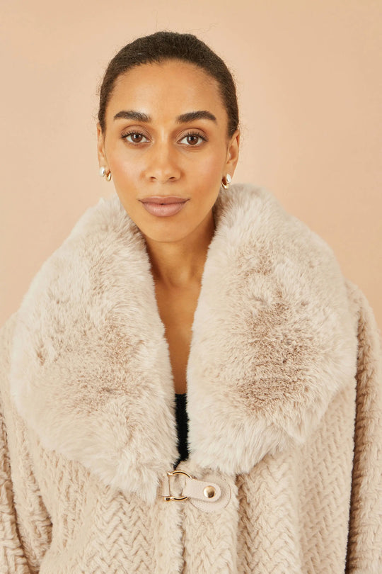Woman wearing Yumi beige textured fur lined cape with oversized faux fur collar and buckle fastening