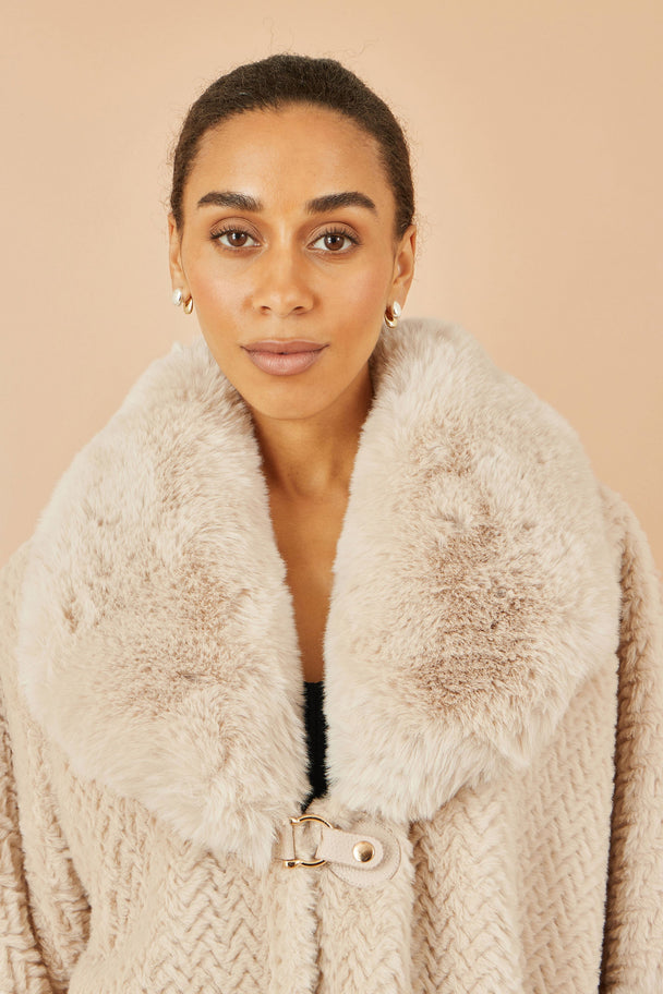 Woman wearing Yumi beige textured fur lined cape with oversized faux fur collar and buckle fastening