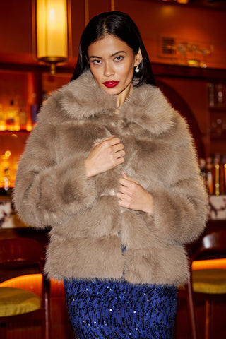 Woman wearing Yumi Coffee Luxe faux fur coat with oversized collar in warm brown tone, styled for party season.