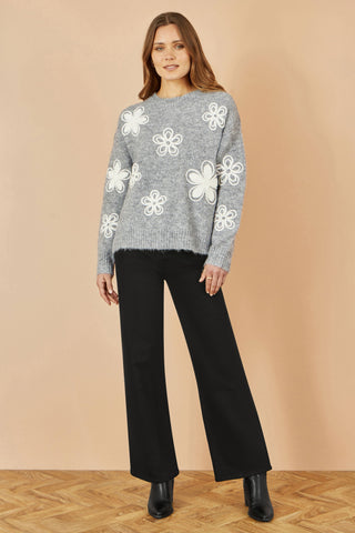 Yumi Grey Relaxed Jumper with crochet flower detail worn with black wide-leg pants and black boots.