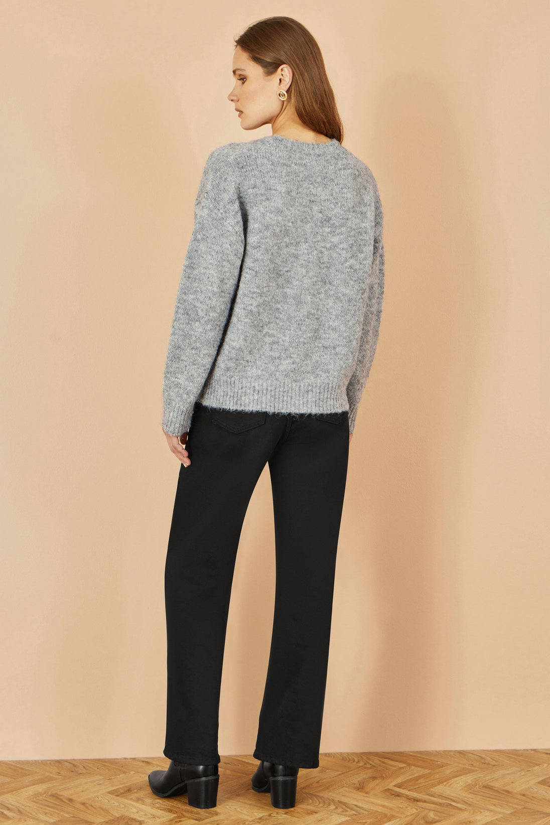 Yumi grey relaxed jumper with crochet flowers worn with black pants and boots back view