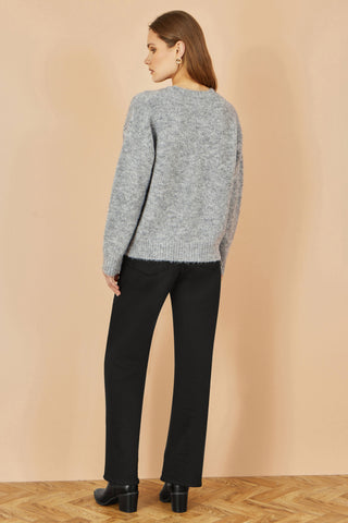 Yumi grey relaxed jumper with crochet flowers worn with black pants and boots back view