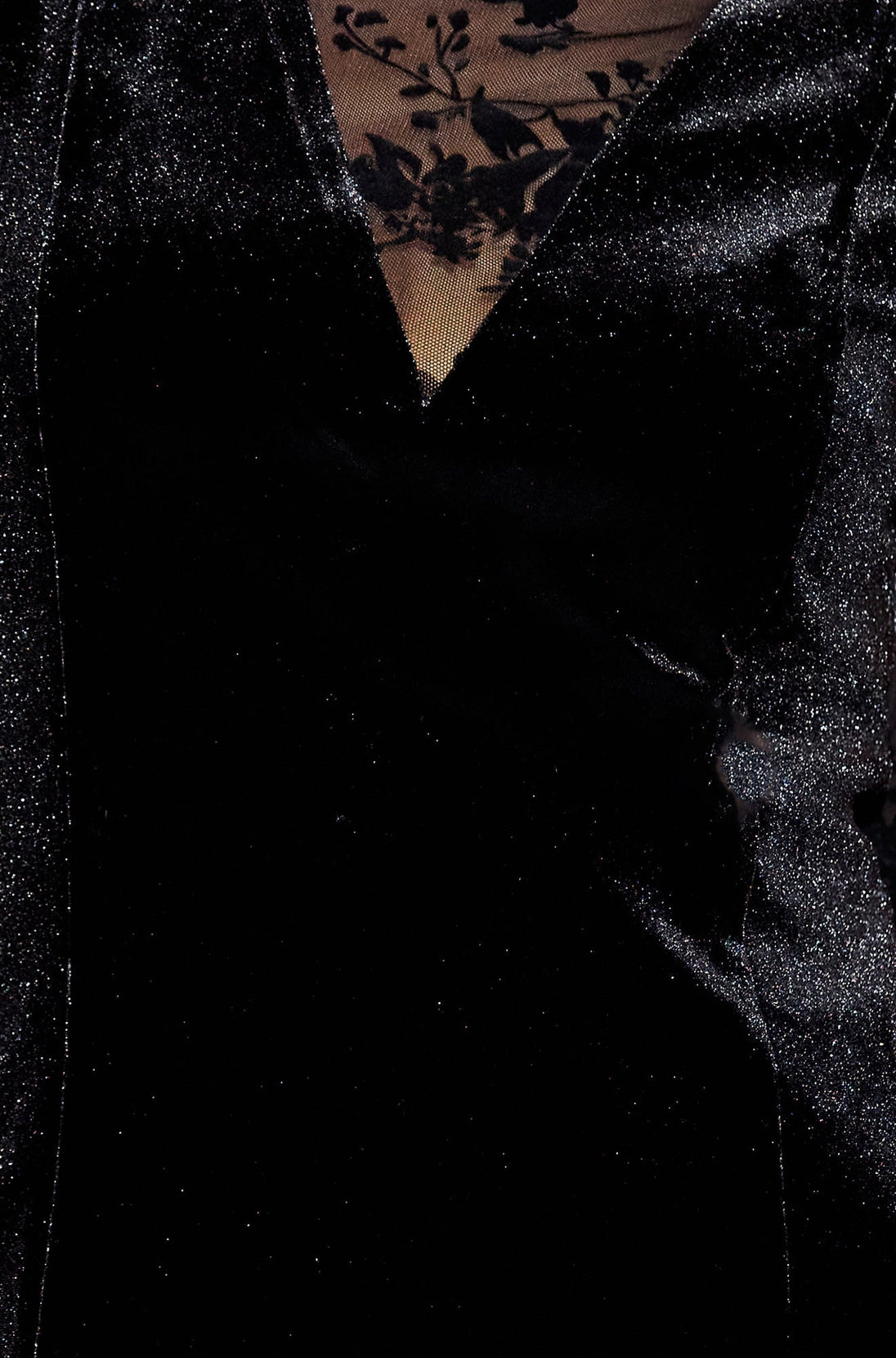 Close-up of black fitted velvet dress with sheer floral sleeves showing texture and design details