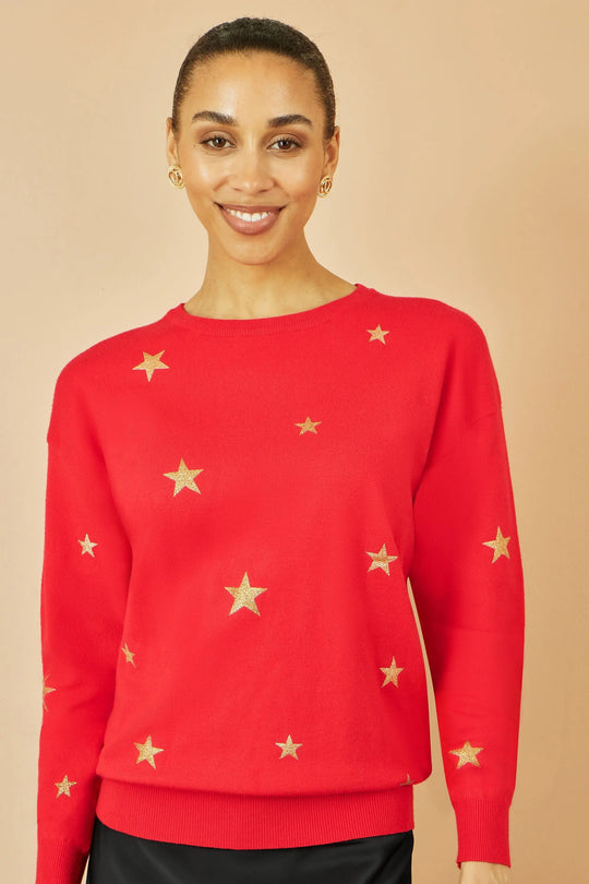 Woman wearing red jumper with gold foil star print and round collar, casual soft knitwear