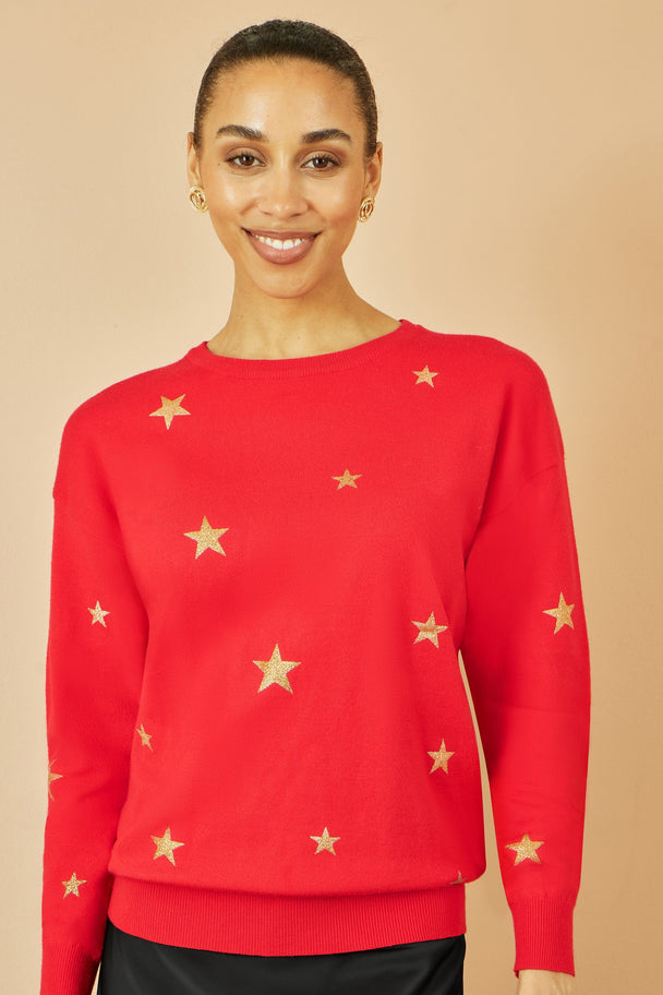 Woman wearing red jumper with gold foil star print and round collar, casual soft knitwear