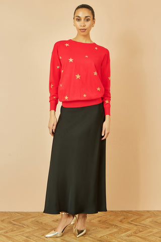 Woman wearing red jumper with gold foil star print and black skirt
