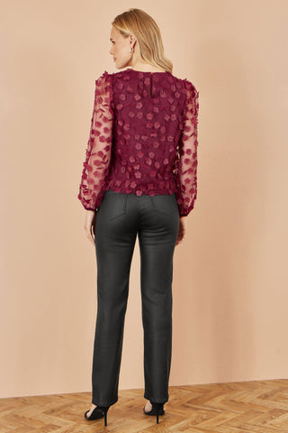 Yumi Burgundy Sheer Sleeve top with floral applique and long sheer sleeves, styled with black trousers.